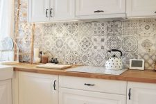 a lovely white cottage kitchen with shaker cabinets, butcherblock countertops, a black and white Moroccan tile backsplash