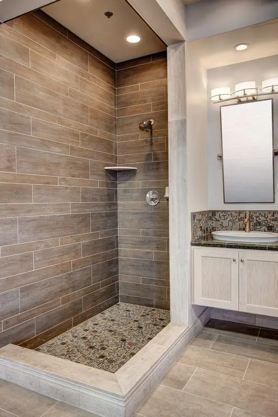 a mid-century modern bathroom clad with stone and wood look tiles, a white vanity, a mirror and a round sink is amazing