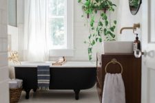 a mid-century modern bathroom with white subway tiles and penny ones, with a black clawfoot tub, a floating vanity and potted plants