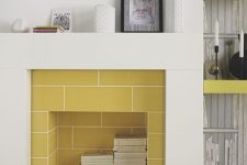 a modern sleek fireplace clad with yellow tiles, with books stored inside is a real centerpiece in a modern living room
