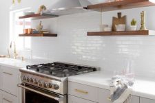 a neutral farmhouse kitchen with a whiye skinny tile backsplash, countertops and thick floating shelves and gold touches