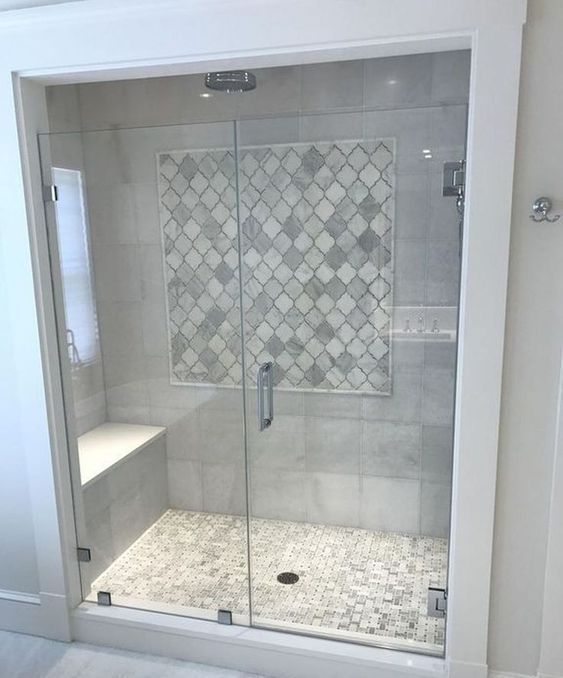 a neutral modern bathroom clad with concrete and marble arabesque tiles in the shower space and with glass doors looks cool