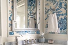 a pretty powder room with chinoiserie wallpaper, a mirror in a cool frame, a console sink and white textiles is a bold idea