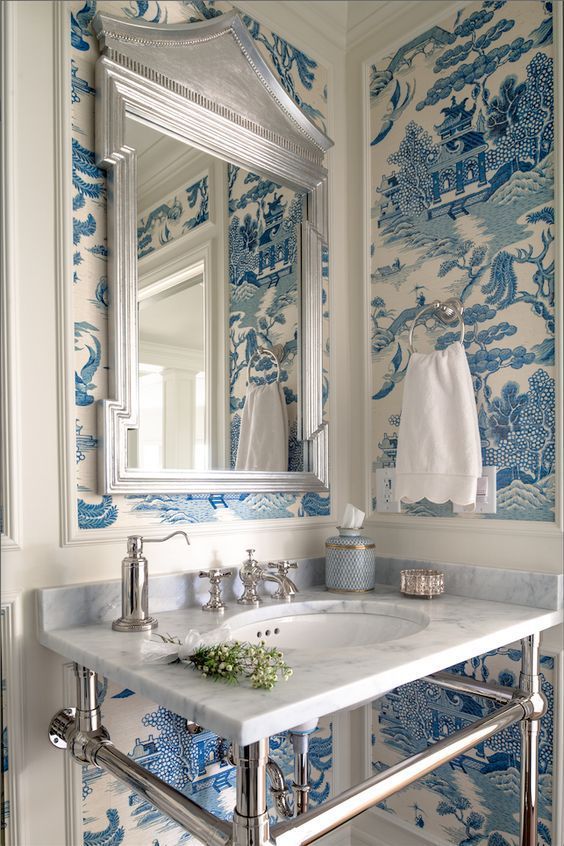 a pretty powder room with chinoiserie wallpaper, a mirror in a cool frame, a console sink and white textiles is a bold idea