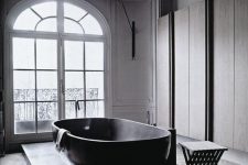 a refined contemporary bathroom with sleek storage units, a platform with a large bathtub and a black stool is amazing