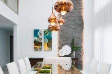a refined dining space with a reclaimed wood table and a glass tabletop, copper pendant lamps and potted moss is amazing