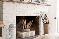 a rustic white brick fireplace with a basket, a bucket with branches, vintage urns and moss, pinecones and branches
