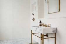 a serene modern bathroom with a geometric floor, a console sink,a shower space clad with stone and neutral tiles, touches of brass is chic