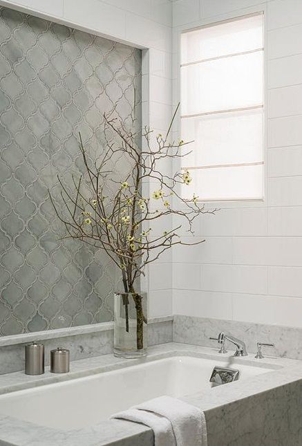 a serene neutral bathroom with white stone and grey arabesque tiles, chromatic touches and a window with frosted glass
