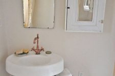 a shabby chic bathroom with a pedestal sink, a vintage mirror and copper faucet, a mirror cabinet, a shabby chic stool and vases