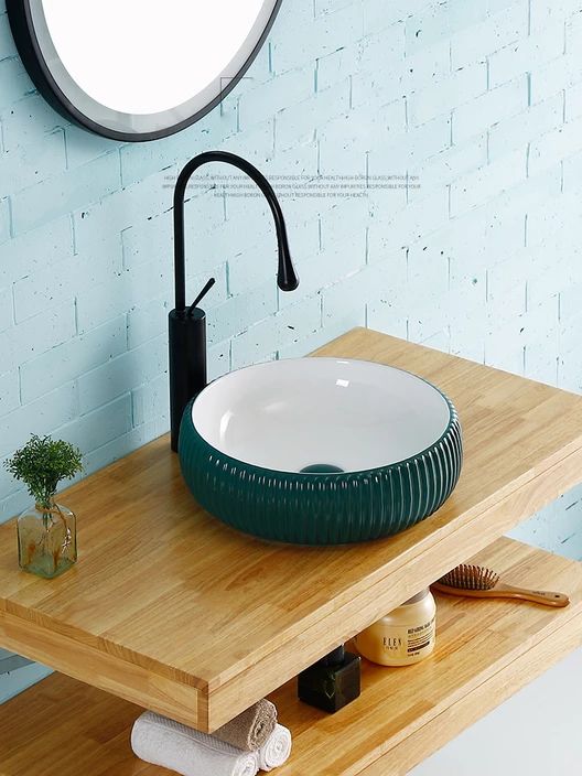 a small light blue bathroom with a floating vanity, an eye-catchy green vessel sink, a black faucet is a very bold and cool idea