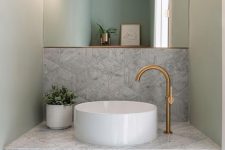 a sophisticated bathroom with grey geo tiles, a marble slab vanity with a round vessel sink and a cool mirror
