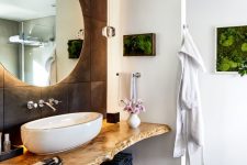 a stylish bathroom with natural touches – vertical planters and a living edge open vanity, an oval vessel sink and a round lit up mirror