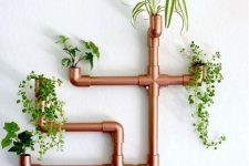 a unique wall-mounted copper fixture used as a planter for several plants is a creative and bold idea