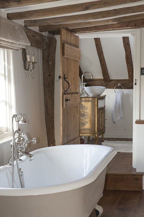 a vintage bathroom with wooden beams and floors, a separate space with a vintage vanity and a clawfoot bathtub