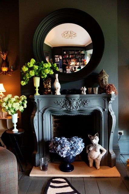 a vintage black fireplace with a refined mantel, some hydrangeas, statues, pretty decor and candleholders is a lovely idea