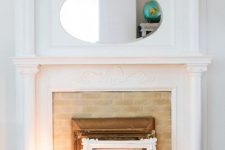a vintage built-in fireplace with a white mantel, a mirror and some mirrors, frames and candles on display is very chic