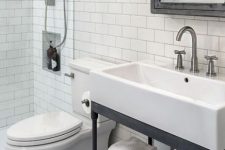 a vintage farmhouse bathroom clad with penny and subway tiles, a console sink, a shower space and a mirror cabinet