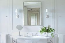 a vintage neutral bathroom with a large console sink, white penny tiles, a pendant lamp on chain and a bucket with blooms