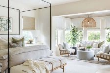 a welcoming neutral farmhouse bedroom with a canopy bed, an upholstered bench, a sitting zone with a sofa, chairs and an ottoman