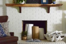 a white brick fireplace styled with tree stumps, a potted plant, a large seashell with whitewashed driftwood for summer