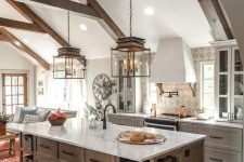a white farmhouse kitchen with shaker cabinets, a stained kitchen island, wooden beams and elegant pendant lamps hanging down
