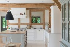 a white farmhouse kitchen with shaker cabinets, white stone countertops, a light aqua kitchen island, wooden beams on the ceiling