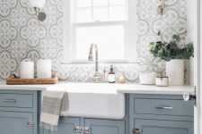 an airy blue kitchen with lovely Moroccan tiles, white stone countertops and neutral fixtures is a very chic and serene space