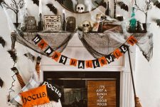 06 a colorful Halloween fireplace with a bold garland, lots of natural and faux pumpkins, printed pillows, black spider web, black bats on the wall
