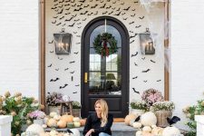 08 a farmhouse front porch done with lots of heirloom pumpkins, blooms in baskets and black paper bats covering the wall is amazing