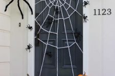 08 a stylish Halloween porch with pumpkins on the steps, a spiderweb and lots of black spiders of various sizes is very easy to recreate