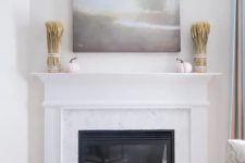 13 a built-in fireplace with pastel and neutral pumpkins in front of it, wheat and pumpkins on the mantel and a lovely artwork