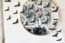 13 a round mirror covered with spider web and with black paper bats is a cool solution for a Halloween space