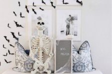 15 an entryway bench with printed pillows, a skeleton, a grid gallery wall and black paper bats on it is a cool idea
