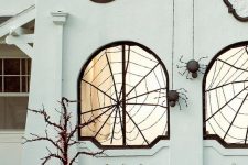 15 outdoors styled with black spiderwebs and black spiders hanging down is a cool idea for Halloween and looks wow