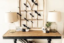 18 a stylish rustic vintage console table with black and white pumpkins, a skull, a vintage window frame and black paper bats covering it