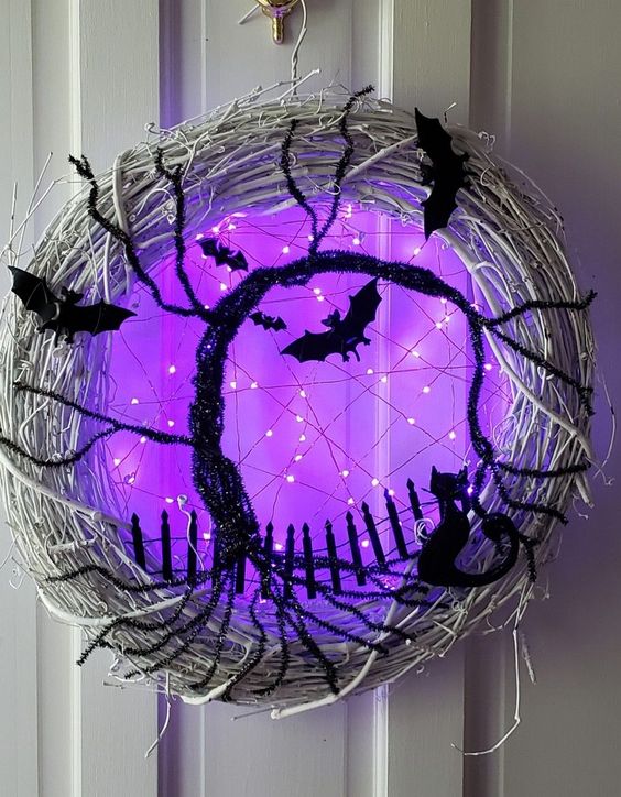 a gorgeous glowing Halloween wreath of whitewashed vine, black bats and cats, a black bottle cleaner tree and purple lights is breathtaking