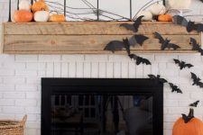 19 a rustic Halloween fireplace with orange pumpkins on the mantel, branches, black paper bats on the fireplace and wall