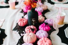 20 a bright pink Halloween party tablescape with a black table runner, pink and peachy pumpkins, black spiders and a black vase with dried and faux blooms