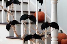 23 a branch covered with black paper bats with red eyes and pumpkins on the steps to style the space for Halloween easily