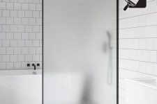 23 a contemporary black and white bathroom with two types of tiles and a frosted glass divider that keeps water in the bathing zone