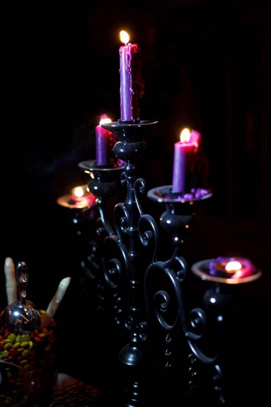 a refined black candelabra with purple candles is a beautiful decoration for Halloween and it looks cool and chic