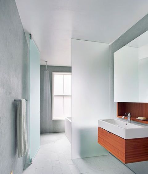 a plane of frosted glass separates the wet side of the bathroom, with the open shower, from the dry side