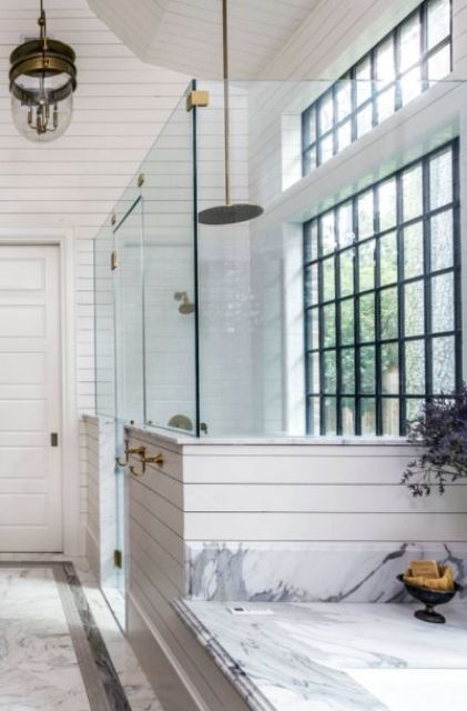 a white farmhouse bathroom with a glazed black frame wall, pendant lamps and white marble looks amazing