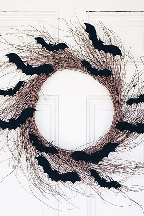 a simple textural vine Halloween wreath covered with black paper bats is a stylish idea that you can easily DIY
