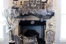 Halloween fireplace styling with bats, spider web, a skeleton, a pillow, branches and a bunting is a cool idea