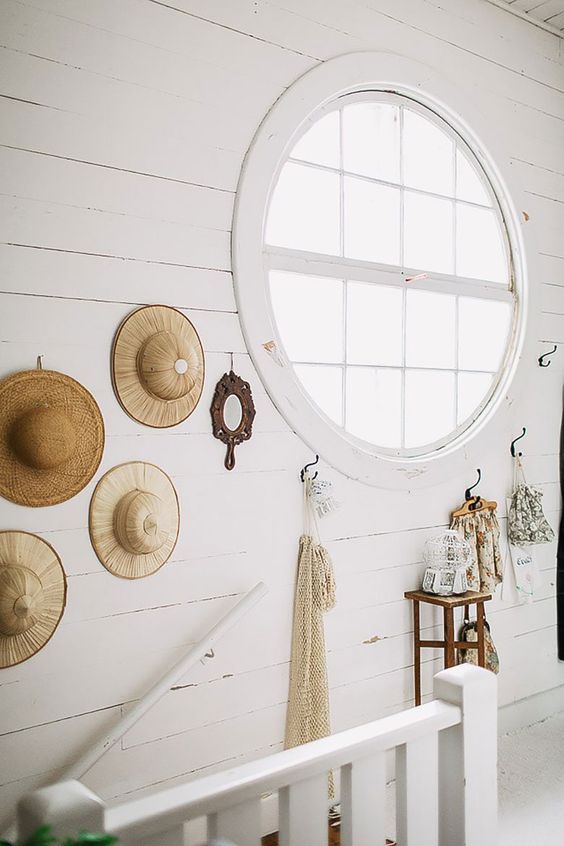 a Nordic staricase space done with white paint and a large porthole window that allows much light inside