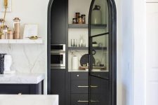 a black and white kitchen with a glass arched door that leads to a pantry with applainces and is a perfect solution for the style of the space