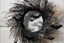 a black branch Halloween wreath with lights and black bats is a cool idea for front door decor and is elegant and stylish