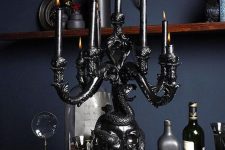 a black skull covered with a snake candelabra with black candles is an adorable decoration to rock at Halloween